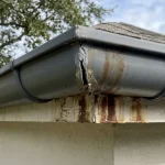 Close-up of a half round miters leak at a 90-degree outside miter showing a visible sealant gap on a half round gutter run